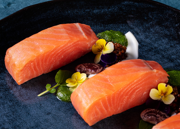 hot-smoked-salmon-plated-with-arugula-pesto-mustard-seeds-and-edible-flowers-feature